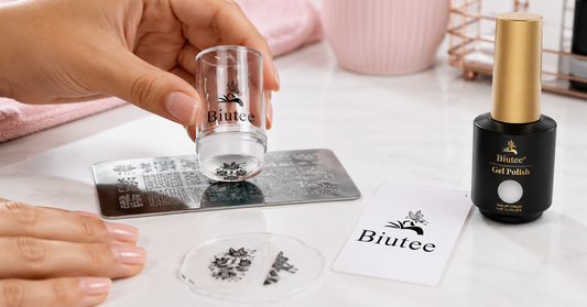Clear nail stamper picking up a patterned design from a stamping plate beside a BIUTEE nail stamping kit