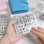 BIUTEE nail stamping plates being cleaned with a lint-free wipe beside the real stamping kit